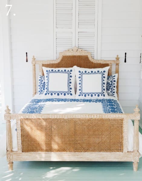 natural cane and white was bed with blue embroidered bedding 